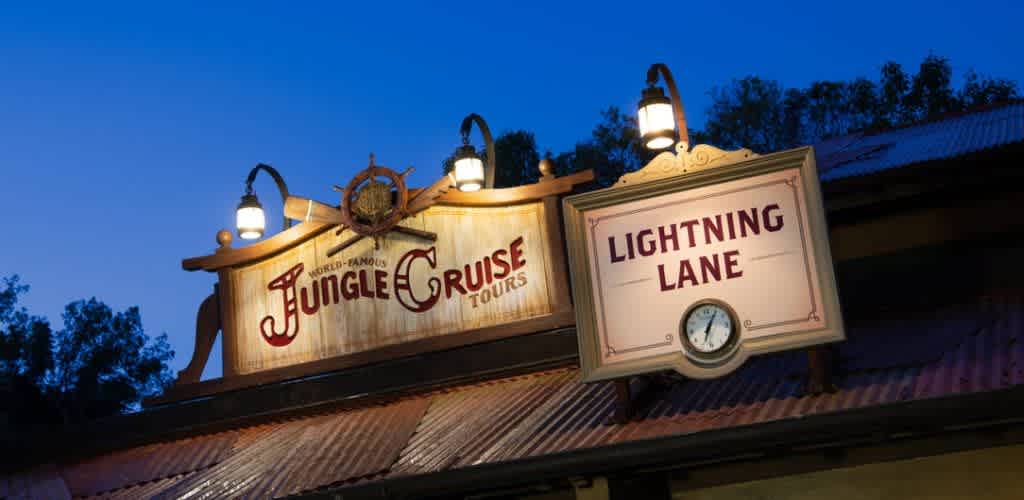 Sign for Jungle Cruise Tours and Lightning Lane at dusk with lamps and a blue sky background
