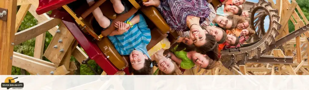 Group of children smiling and enjoying a wooden roller coaster ride outdoors on a sunny day
