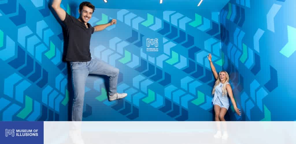 Two children are playing and pretending to climb a colorful geometric wall at the Museum of Illusions.