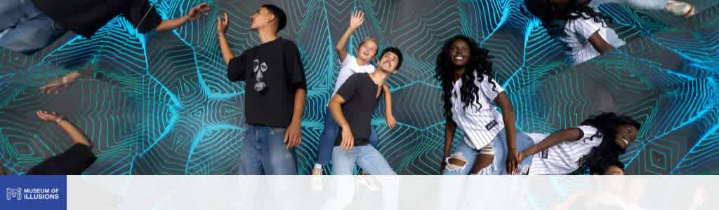 Group of diverse children smiling and playing in front of an illuminated digital wall at a museum of illusions