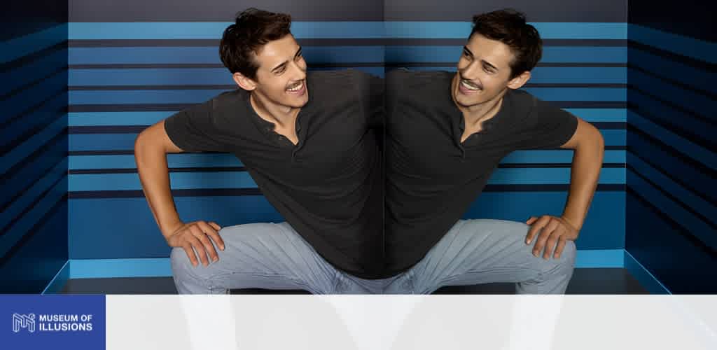 A person appears twice in the image, smiling and posing in front of a colorful, striped background at the Museum of Illusions.