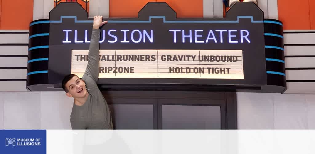 A smiling woman reaches up and touches an illuminated sign for Illusion Theater at the Museum of Illusions.