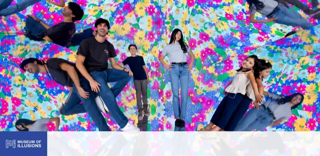 Group of young adults standing and lying on a colorful floral illusion mirror wall at Museum of Illusions